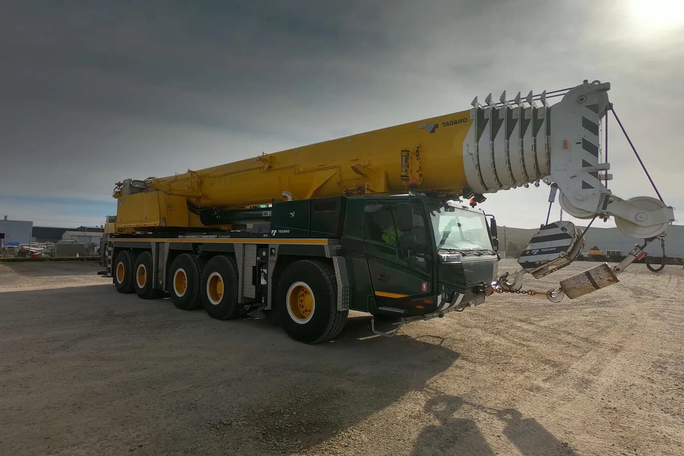A Tadano all-terrain crane with its boom extended at sunset